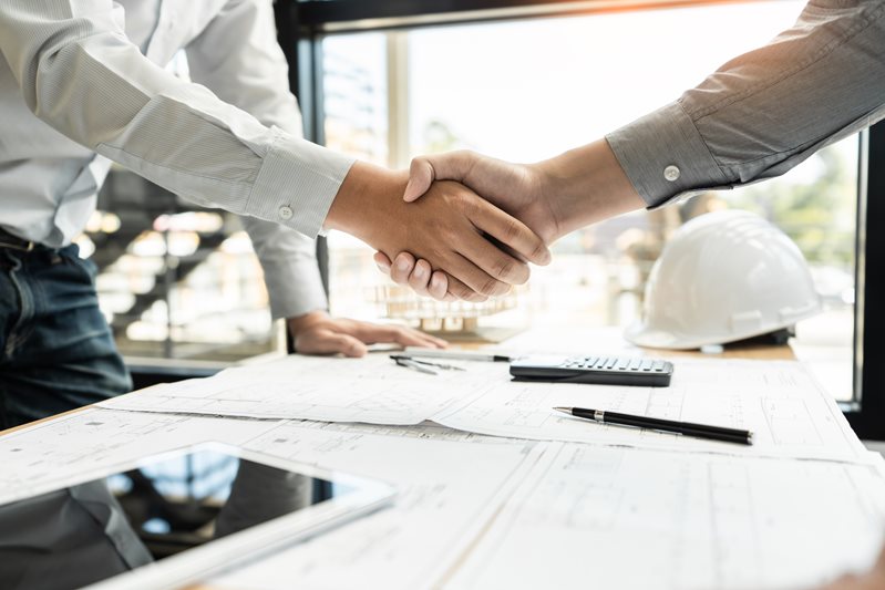 handshake closeup with contracts and documents
